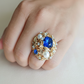Close-up of a ring with a blue gemstone on a finger
