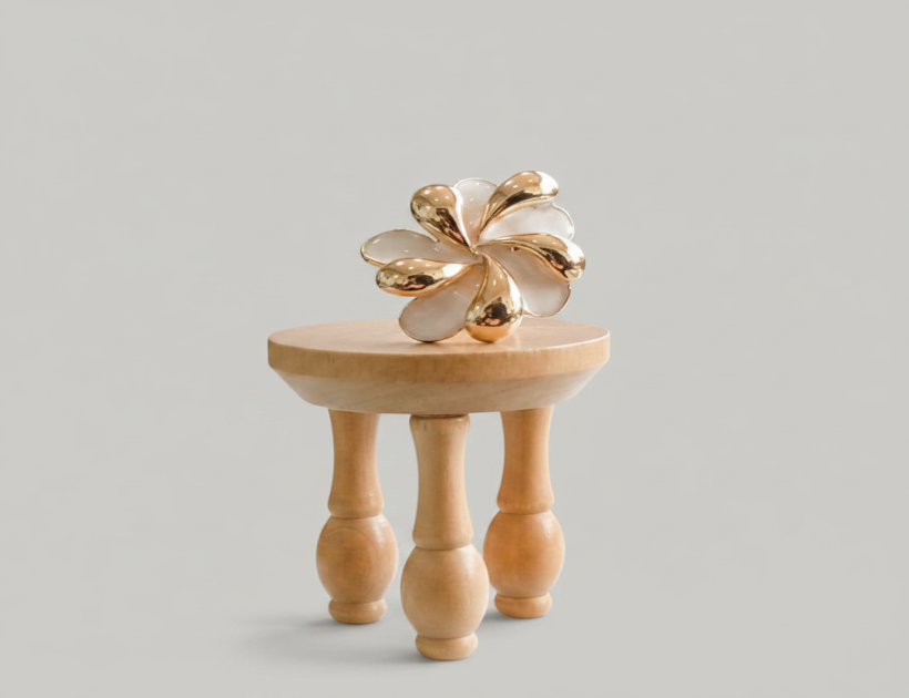 Gold decorative item on a wooden stand in a room with chairs and a table.
