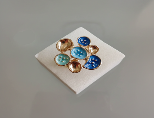 Pair of earrings with blue and gold stones on a white card